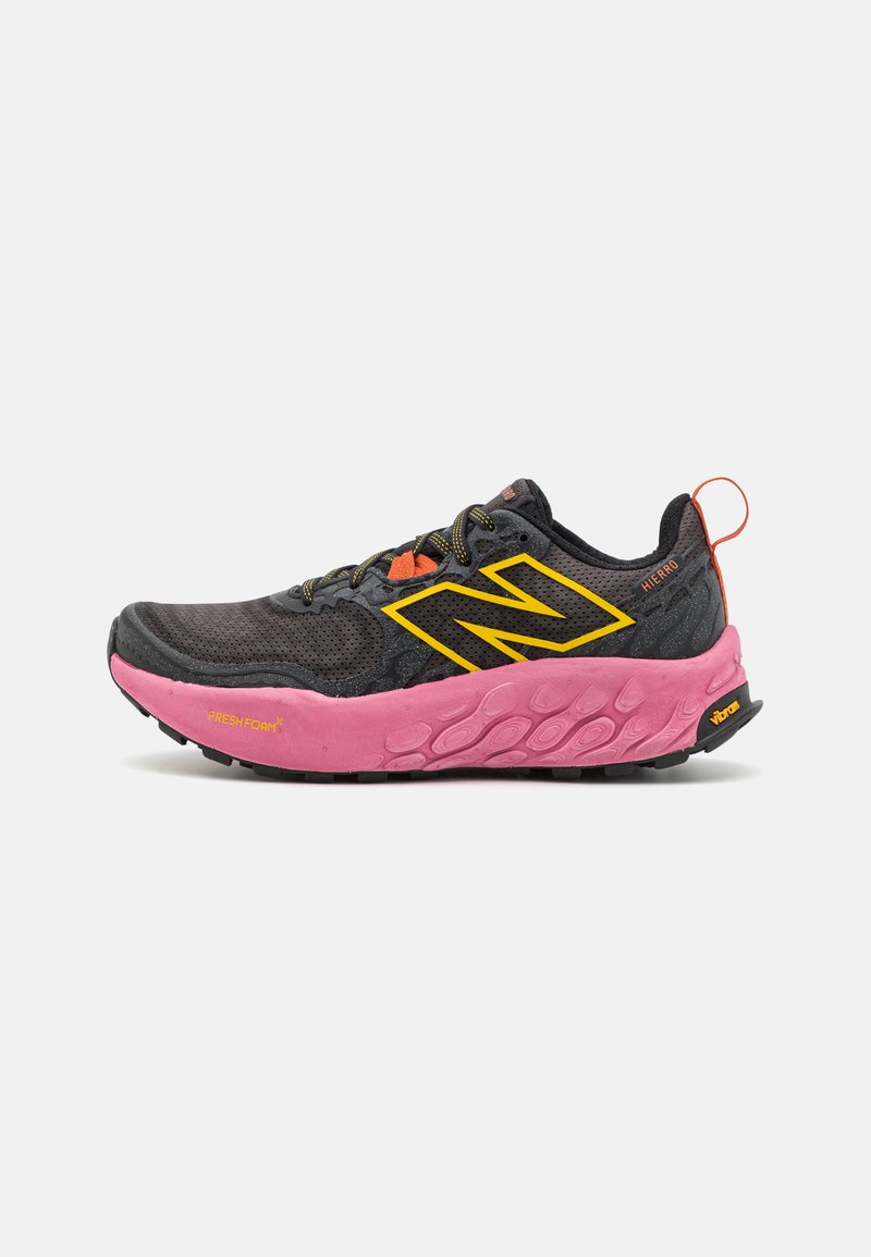 Scarpa da trail running nera con suola rosa, dettagli gialli e parte superiore in mesh grigia. Presenta una punta rinforzata e lacci testurizzati.