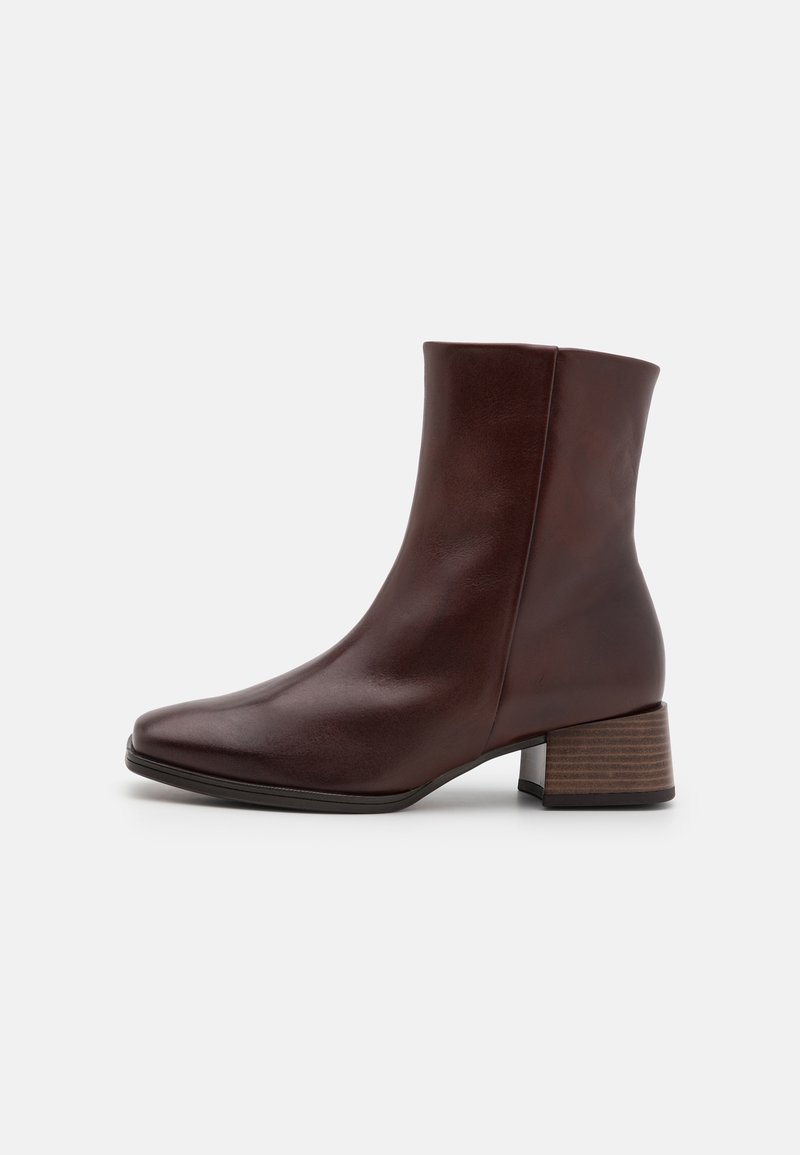 Bottine en cuir marron avec un bout carré, une finition lisse et un talon bloc en bois épais. Design sans coutures ni attaches visibles.