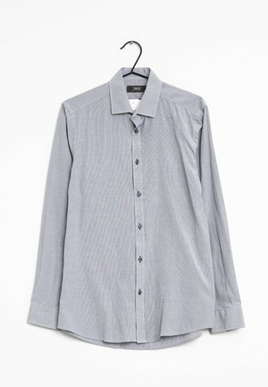Grijs shirt met lange mouwen en een button-down kraag, met een subtiel geruit patroon en donkere knopen aan de voorkant, hangend aan een haak.
