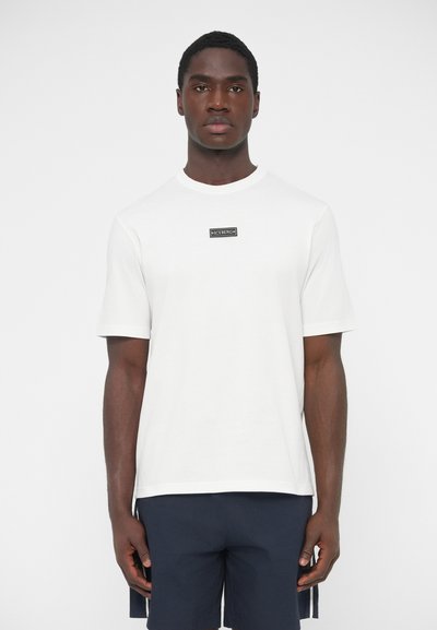 Λευκό κοντομάνικο βαμβακερό μπλουζάκι με μαύρο ορθογώνιο λογότυπο στο στήθος, με στρογγυλή λαιμόκοψη και άνετη εφαρμογή.