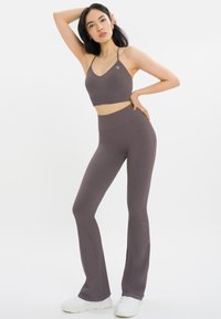 Grijze ribbel sportbeha en bijpassende hoge, uitlopende legging, gemaakt van rekbare stof, met een aansluitend ontwerp en logo-detail op de beha.
