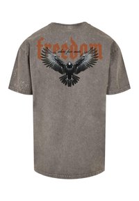 Grå t-shirt med et nedslidt udseende, korte ærmer og et grafisk billede af en ørn med ordet "frihed" i orange ovenfor.