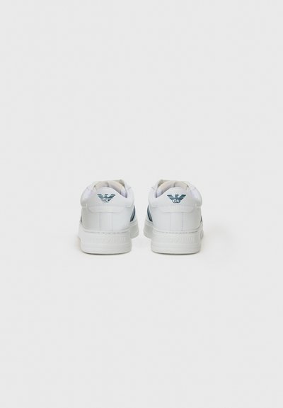 Vita sneakers med en slät läderfinish, med teal-accenter på baksidan och en gummisula. Inkluderar en präglad logotyp på hälen.