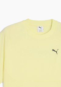 Lysegul atletisk skjorte med korte ærmer og rund halsudskæring, prydet med et sort Puma-logo øverst til venstre.