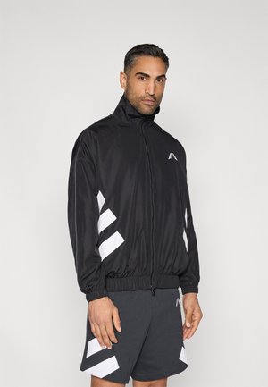 Black zip-up jacket with high collar, elastic cuffs, and white diagonal stripes. Worn over gray shorts featuring matching accents.