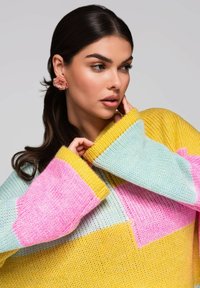 Meerkleurige gebreide trui met gele, roze en lichtblauwe delen, met een losse pasvorm en oversized mouwen. Dikke textuur.