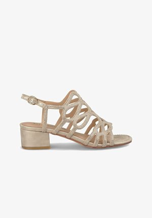 Sandalo beige con tacco, dotato di cinturini incrociati, arricchito da accentuazioni metalliche, punta tonda e tacco basso per una maggiore stabilità.