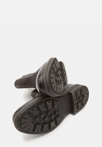 Cizme negre până la gleznă, cu un superior din suede și talpă din cauciuc rezistent. Prezintă un model texturat al tălpilor pentru aderență și suport.