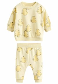 Dzeltena kokvilnas divdaļu komplekts, kas ietver garām piedurknēm topu un bikses, abiem ar vistas druku. Ribotas aproces un jostasvieta.