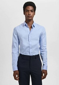 Lichtblauw overhemd met een gladde textuur, slim fit ontwerp, puntige kraag en lange mouwen, gecombineerd met donkere broek.