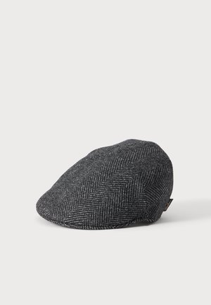 Dark gray herringbone flat cap with curved peak and small fabric tag on side against a plain light background.