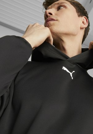 Sudadera con capucha negra de textura suave, con un logo blanco de Puma en el pecho; diseñada con cuello alto y un ajuste relajado.