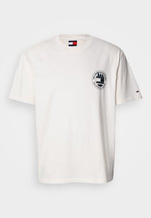 Fehér pamut póló rövid ujjakkal, kerek nyakkivágással és bal mellrészen kör alakú logóval. Kis színes részlet az ujjon.