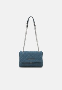 Quiltad blå tyghandväska med en silverkedjeslunga, med en framflik och en inlägg med logotyp. Slät yta och strukturerad form.