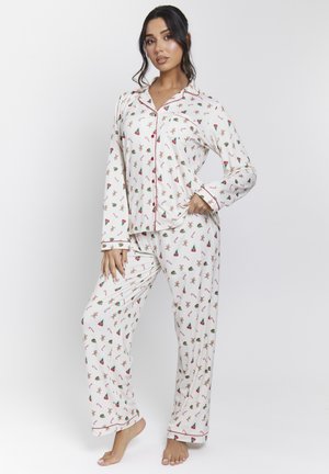 White pajama set with red trim, featuring a playful print of gingerbread men and Christmas trees. Long sleeves and loose-fit pants.