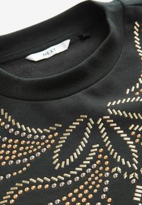 Felpa nera con colletto a girocollo a costine, decorata con embellishments metallici oro, bronzo e argento in motivi geometrici.