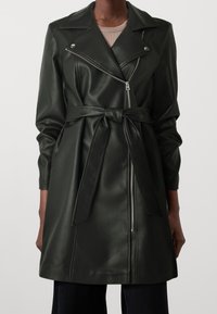 Abrigo de trench de cuero verde oscuro con cintura ceñida, cremalleras plateadas y cuello de solapa. Presenta mangas largas y una textura suave.