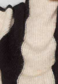 Tissu tricoté doux et pelucheux avec des rayures ondulées noires et blanches et une texture côtelée.