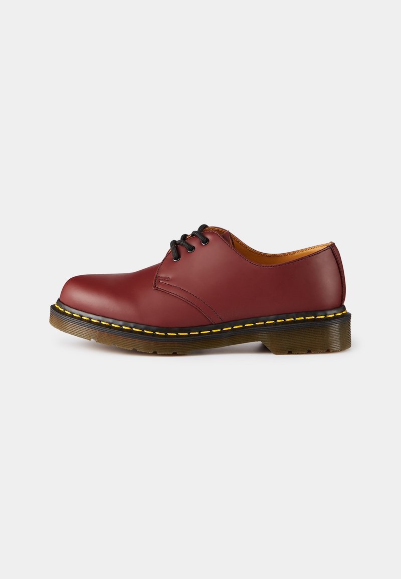 Chaussure à lacets en cuir lisse rouge foncé avec lacets noirs, surpiqûres jaunes sur la semelle et semelle extérieure en caoutchouc marron translucide.