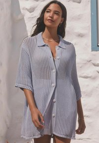 Svijetloplava pletena cardigan jakna s ovratnim izrezom, oversized kroja, kratkim rukavima i zatvaranjem na gumbe, s rebrastom teksturom i otvorenim tkanjem.