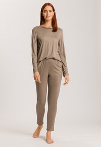 Beige långärmad topp med en rundad halsringning, parat med matchande åtsittande byxor. Mjuk, elastisk tyg med sidofickor och sprund vid anklarna.