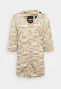 Camisa de botão de manga curta em padrão ondulado bege e verde pastel, com colarinho e logótipo bordado, tecido texturizado e botões de madeira.