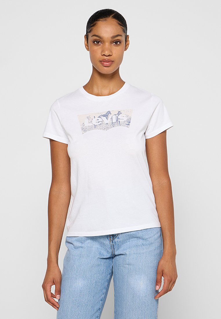 Camiseta blanca de algodón con forma ajustada. Presenta un diseño gráfico azul en el frente. Mangas cortas y cuello redondo.