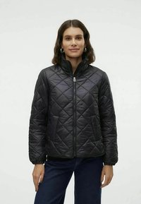 Casaco preto acolchoado com gola alta, fecho de correr à frente e punhos elásticos. O material parece suave com uma textura almofadada. Ajuste casual.