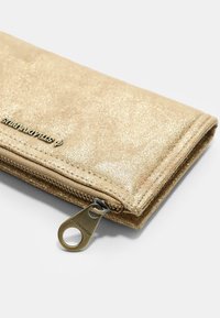 Zlatá třpytivá peněženka vyrobená z umělého materiálu, s uzávěrem na zip, hladkým povrchem a detailem loga na přední straně.