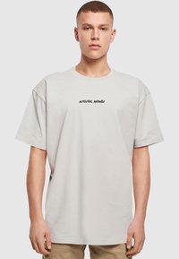 Lysegrå oversize t-shirt lavet af bomuld, med en sort teksttryks "Artistic Minds" på brystet, rund halsudskæring og korteærmer.