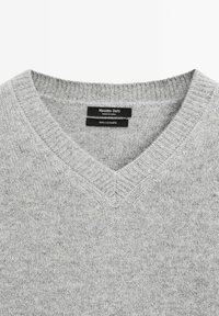Grauer Kaschmirpullover mit V-Ausschnitt, ausgestattet mit einem gerippten Kragen und weicher Textur. Etiketten weisen auf Marke und Materialzusammensetzung hin.
