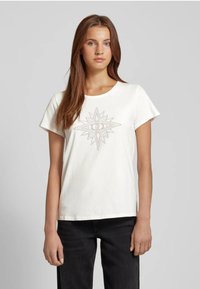 T-shirt bianca a maniche corte con scollo rotondo, caratterizzata da un motivo geometrico a stella centrale in grigio. Realizzata in morbido cotone.