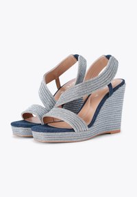 Sandali con tacco a cuneo con cinturini in tessuto argentato e base in denim. Presentano cinturini incrociati e un tacco a cuneo argentato con texture.