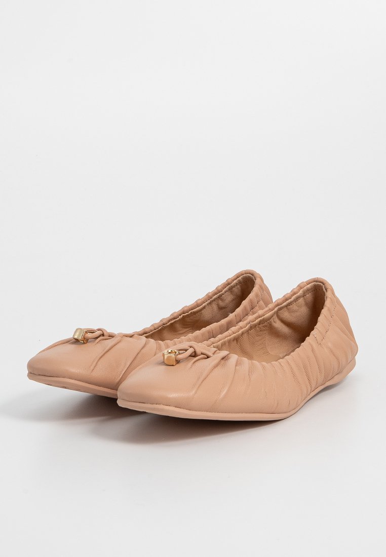 Beige leren ballerina's met een elastische rand, ronde neus en kleine gouden accenten, met een zachte textuur op de bovenkant.