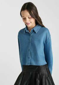 Lichtblauwe spijkerblouse met een cropped ontwerp, lange mouwen en subtiele sprankelende accenten. Aansluitend kraag en knoopsluiting aan de voorkant.
