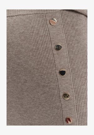 Beige geripptes Gewebe mit fünf glänzenden goldenen runden Knöpfen, die vertikal auf einem gestrickten Kleidungsstück angeordnet sind.