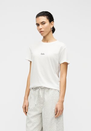 Hvid bomuld T-shirt med rundt halsudskæring og korte ærmer, med en lille sort logo "Lala" trykt på brystet.