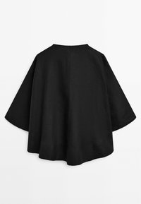Černý lněný top s širokým, volným designem. Zadní část má kulatý výstřih a elegantní, minimalistickou siluetu. Hladká textura.