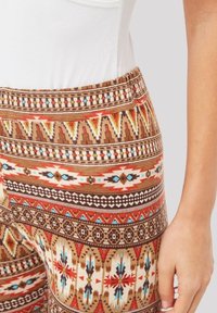 Leggings estampados con una mezcla de diseños geométricos en marrón, rojo y azul, fabricados en un tejido suave y texturizado, con una cintura ajustada.