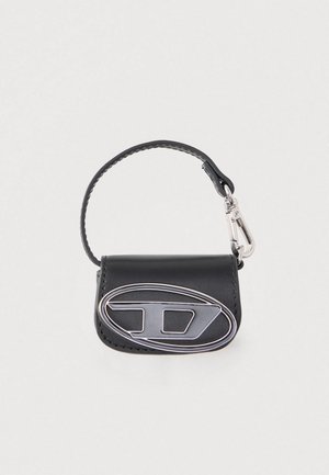 Melnas ādas mini soma ar augšējo rokturi un lielu sudrabainu metāla "D" logotipu uz priekšējā vāka.