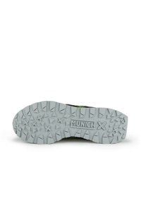 Suela de zapato con una superficie de goma gris texturizada que presenta un patrón de grabado triangular. Marca "MUNICH" visible en el área del talón.
