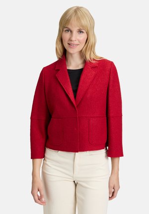 Veste rouge courte en tissu texturé, avec un col cranté, deux poches avant et des manches trois quarts.