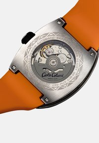 Edelstahl-Automatikuhr mit transparentem Gehäuseboden, orangefarbenem Silikonarmband, gravierten Details und strukturiertem Lünette. Zeigt sichtbare Bewegungsmechanik.