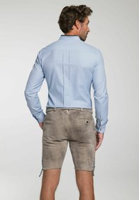 Lichtblauwe button-up shirt met lange mouwen, gecombineerd met grijze suède shorts met zijschoentjes en een achterzakdetail.