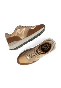 Baskets athlétiques marron et beige avec semelles en caoutchouc, logo "M" sur le côté, lacets et col rembourré, vues de côté et de dessus.