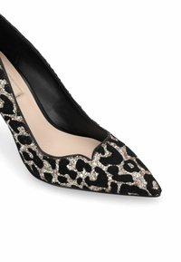 Pompe noire à bout pointu avec un motif léopard en paillettes dorées et argentées. Présente un bord festonné et une doublure intérieure lisse.
