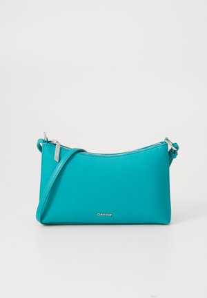 Turquoise leather crossbody bag with silver hardware, rectangular shape, and a zip closure. Features a minimalist design and brand logo.