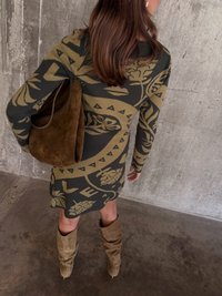 Úpletové šaty s olivovozelenými a khaki botanickými vzormi, doplnené hnedou semišovou taškou a vysokými, voľnými taupe čižmami.