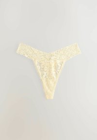 Perizoma in pizzo di un morbido giallo con motivo floreale, caratterizzato da bordi ondulati e una texture trasparente. Design minimalista e delicato.