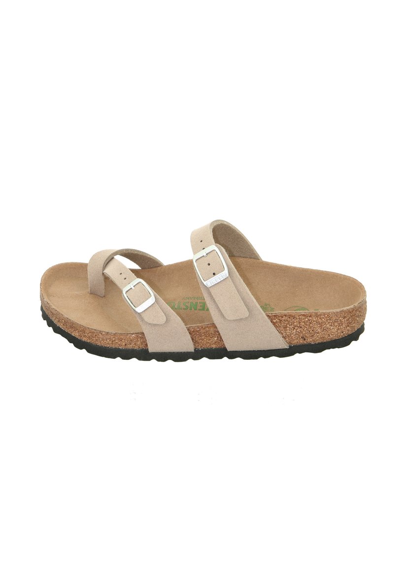 Beige suede sandal with two adjustable straps featuring silver buckles. Cork footbed and textured black rubber sole. Flat design.